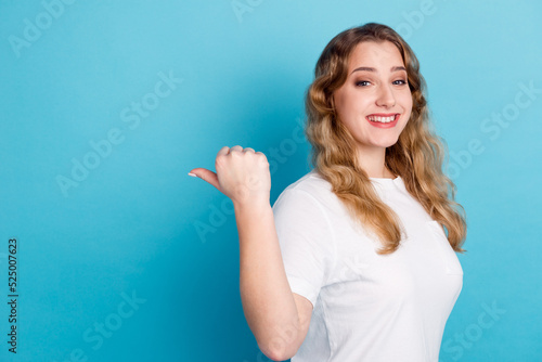 Photo of charming young woman dressed shirt smiling pointing finger empty space isolated blue color background