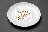 Concept of a global food crisis caused by hunger due to lack of grain. Plate with small amount of grain on plate on black background
