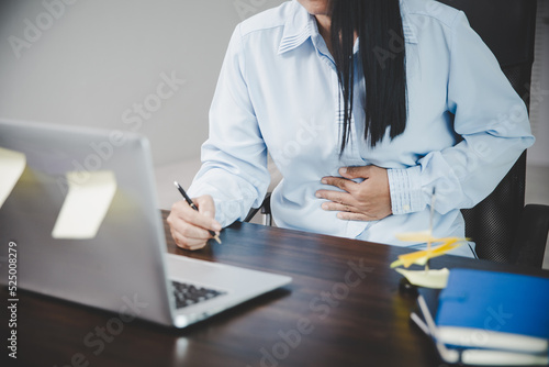 Young asian business woman person sitting at work and has stress pain in her stomach. Concept office syndrome abdomen pain from occupational disease  Female having belly pain and using laptop computer