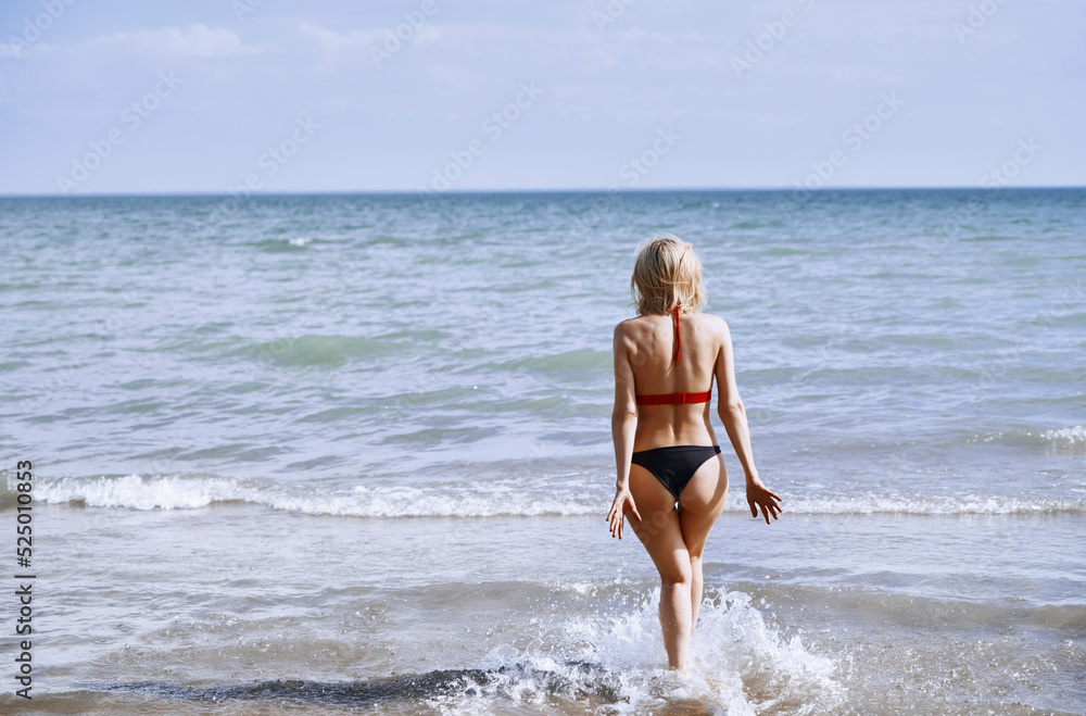 Woman in bikini walking at beach on sunny day Woman in bikini walking at beach on sunny day