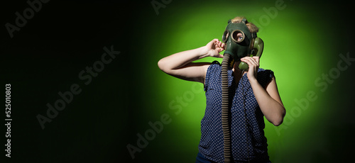 Funny woman in a gas mask calls on a retro phone on a dark background with copy space, hard light. © Sergey