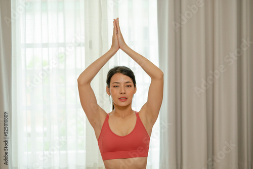 Beautiful asian girl doing yoga at her home.