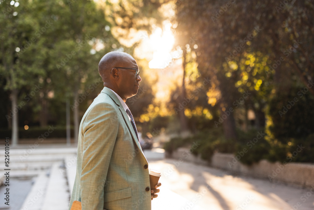 Mature businessman with coffee cup standing in park Mature businessman with coffee cup standing in park