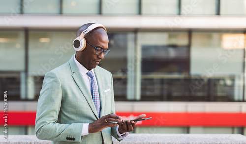Mature businessman wearing wireless headphones using tablet PC