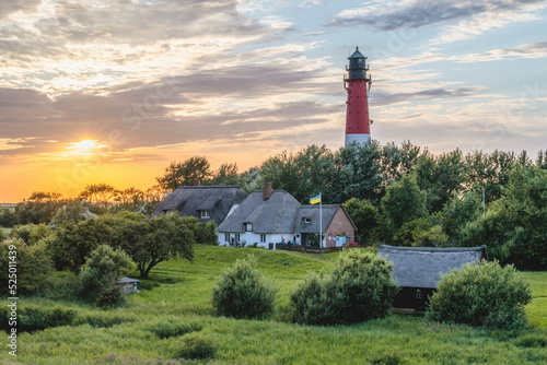 Germany, Schleswig-Holstein, Pellworm, Farmhouses in front of Pellworm Lighthouse at springtime sunset