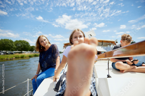 Girl showing feet sitting with family on boat deck photo