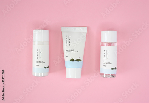 KYIV, UKRAINE - 19 AUGUST 2022: Set of korean skin care products in white tube and mini bottles (lotion, cleanser, tonic) of brand Round lab. Isolated on pink background. Top view.