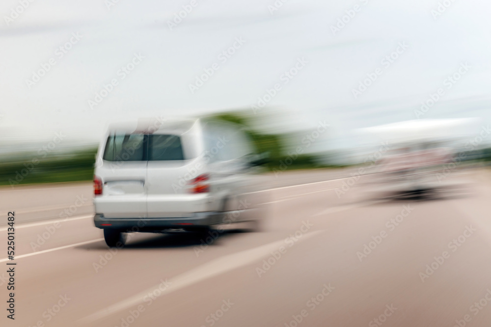 Rear view of unrecognizable blur view of white wagon van driving on highway autobahn