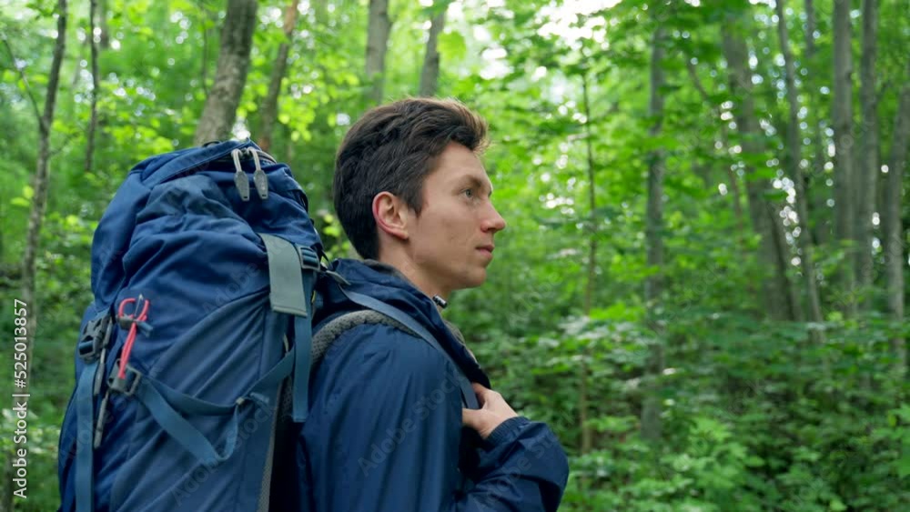 Black-haired young man discovers awesome forest destination standing. Guy camper enjoys hiking in forest. Sunlight breaks through tree branches closeup Black-haired young man discovers awesome forest destination standing. Guy camper enjoys hiking in forest. Sunlight breaks through tree branches closeup
