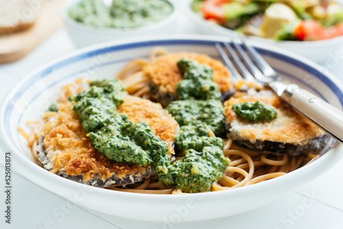 Dish with home made breaded eggplant with spinach pesto, served on spaghetti