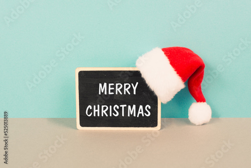 Red Santa Claus hat hanging on a chalkboard, greeting card with merry christmas wishes, winter season 