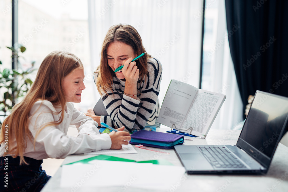Mother and daughter laughing while doing homework Mother and daughter laughing while doing homework