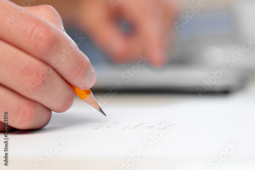 Young businessman writing with a pencil and surfing the internet on a mobile phone