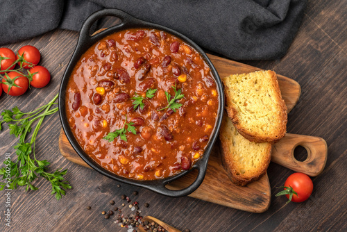 Mexican food chile con carne dish on a wooden backdrop. Bean and corn soup, red bean stew