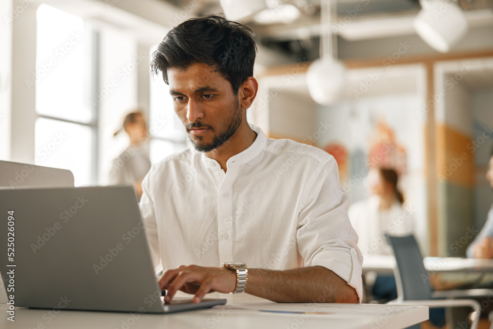 Businessman working laptop while sitting in modern office on colleagues background