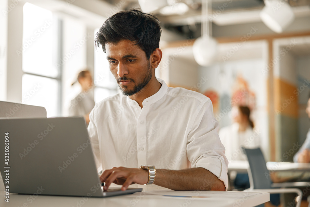 Businessman working laptop while sitting in modern office on colleagues background Businessman working laptop while sitting in modern office on colleagues background