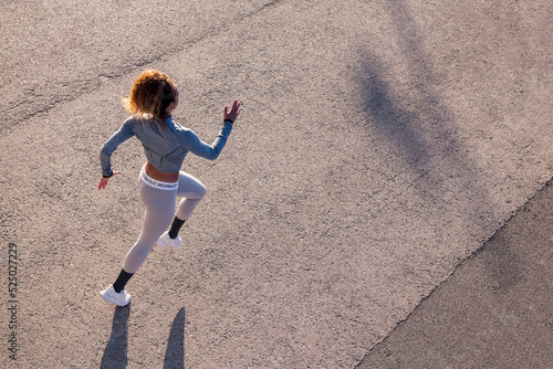 Active runner in sportswear jogging on urban pavement photo
