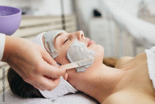 Beautiful and attractive adult woman receiving professional facial care beauty treatment with peeling mask.