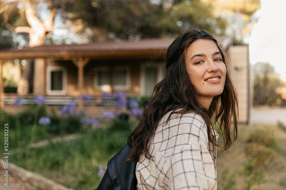 Smiling young caucasian brunette lady looking at camera walking in countryside. Model girl wears casual shirt. Lifestyle concept Smiling young caucasian brunette lady looking at camera walking in countryside. Model girl wears casual shirt. Lifestyle concept