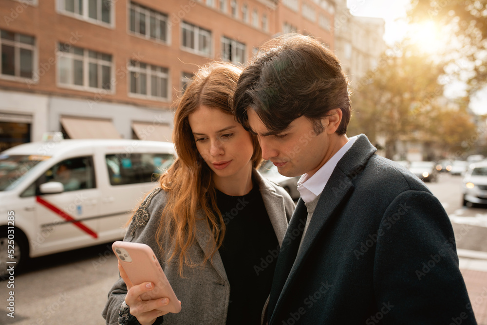 Loving young couple standing using smartphone on street Loving young couple standing using smartphone on street