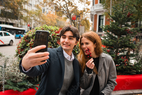 Cheerful romantic couple taking selfie on city street