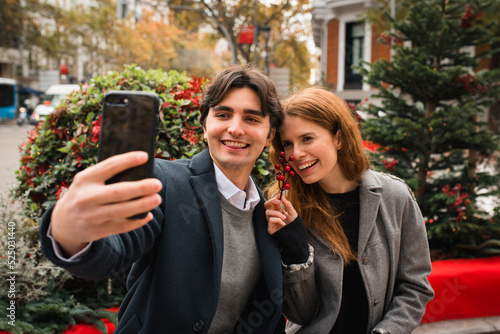 Cheerful romantic couple taking selfie on city street