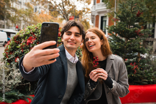 Cheerful romantic couple taking selfie on city street