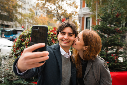 Cheerful romantic couple taking selfie on city street