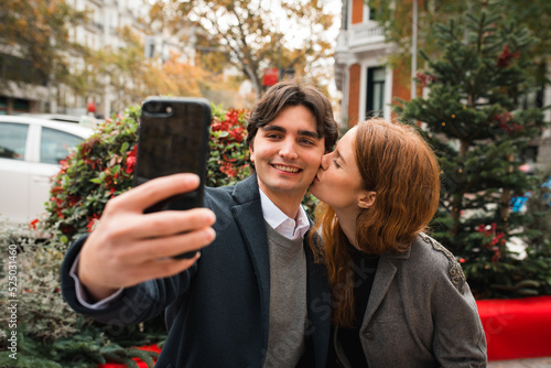 Cheerful romantic couple taking selfie on city street