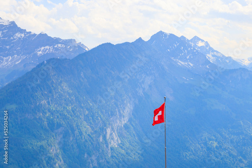 Red Swiss flag over the Swiss Alps background