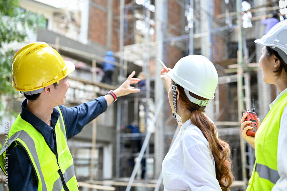 A professional Asian male construction inspector explains the building process to female architects A professional Asian male construction inspector explains the building process to female architects