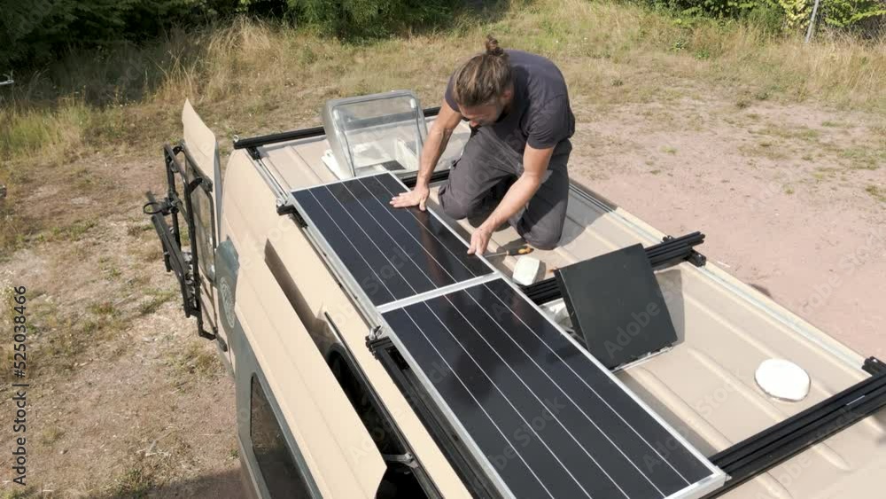 Person working on a solar panel on the roof of a caravan Person working on a solar panel on the roof of a caravan