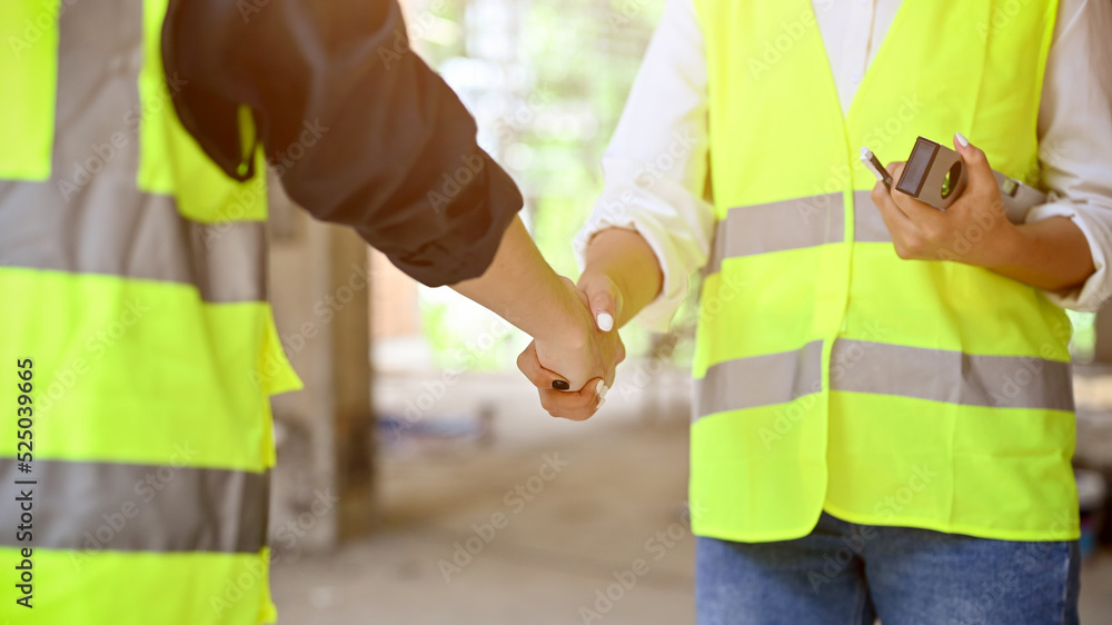 Male civil engineer shaking hand with male construction inspector. cropped