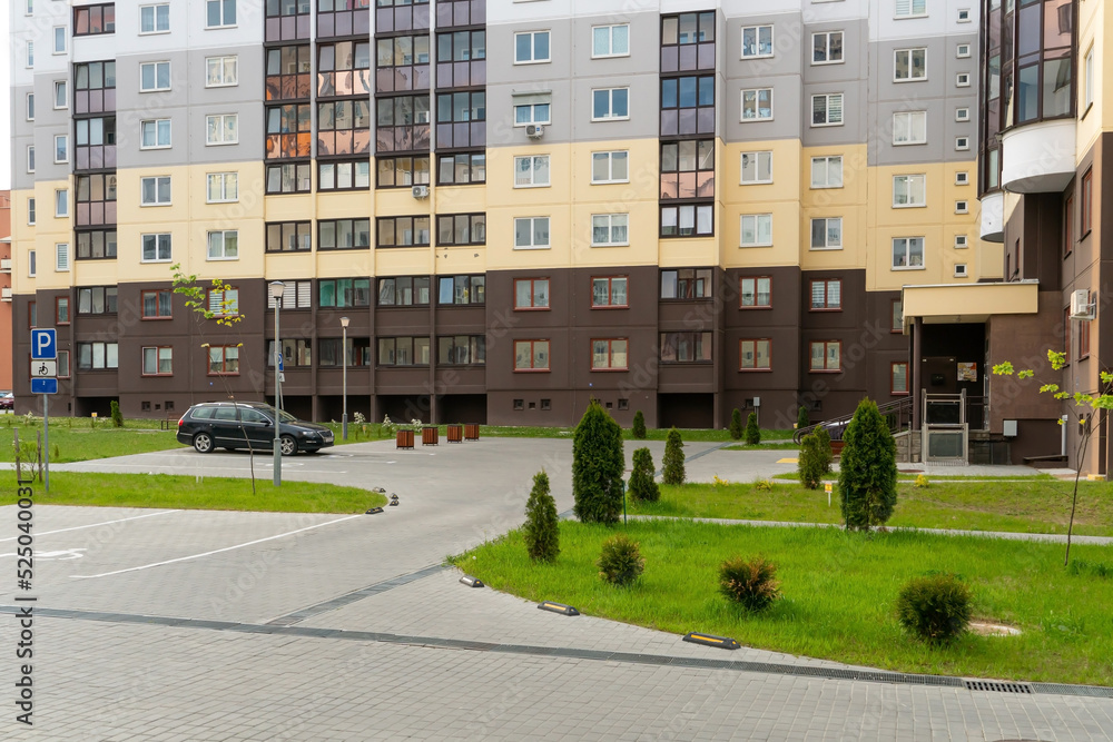 the courtyard of a large multi-storey residential complex in the summer with parking spaces for cars. Parking spaces for drivers with disabilities.