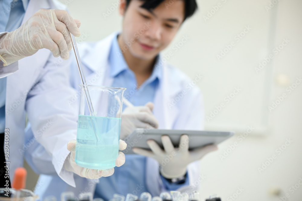 Handsome Asian male scientist working in the lab, recording the experiment results on tablet Handsome Asian male scientist working in the lab, recording the experiment results on tablet