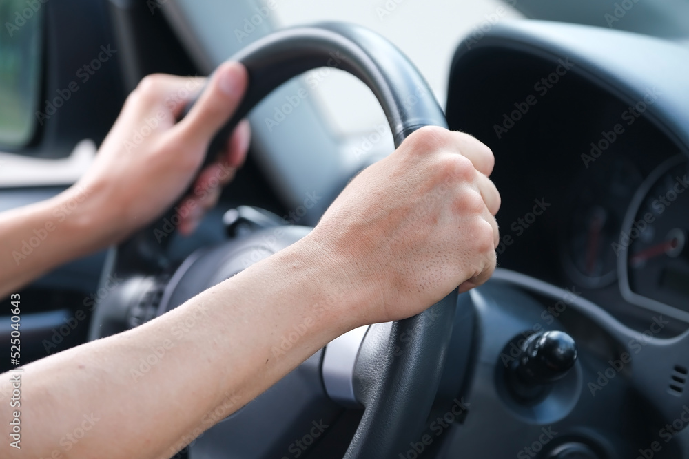 closeup of male hands on the steering wheel of a car 