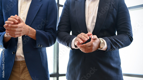 Businessmen are applauding their coworkers during the meeting. cropped image