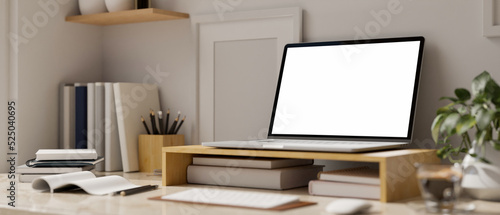 Laptop white screen mockup is on wooden laptop stand and accessories on the table. close-up © bongkarn