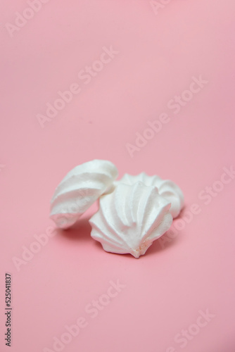 White meringues on pink background. French dessert prepared from whipped with sugar and baked egg whites. Greeting card with copy space
