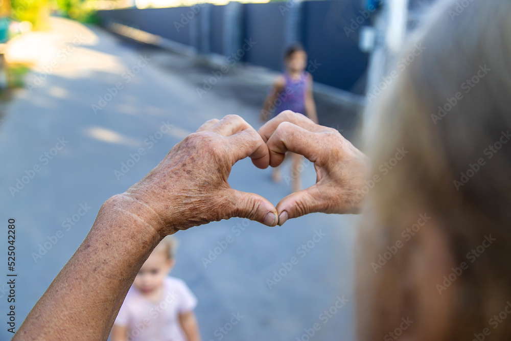 grandmother makes a heart with her hands. Selective focus.