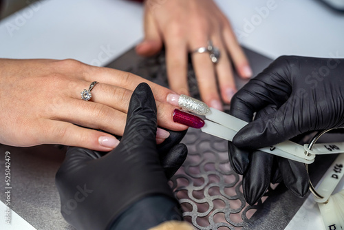 a female client showing the color of the nail tips in a nail salon looking at the camera.
