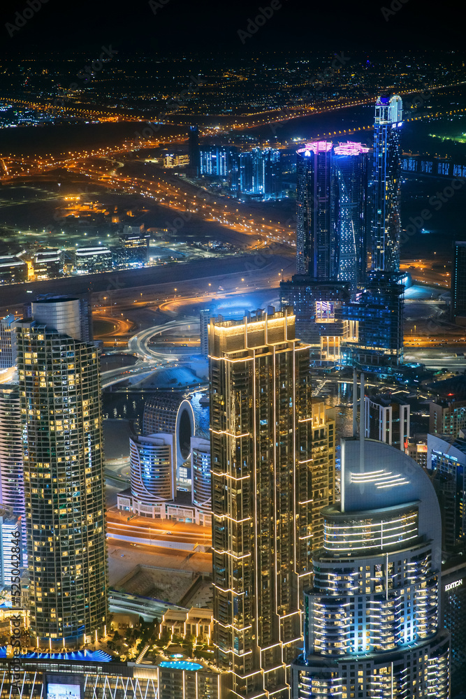 Aerial view of beautiful evening night illuminations scenic view of skyscraper and towers in Dubai. Street night traffic in Dudai skyline. Urban background of Dubai, UAE, United Arab Emirates
