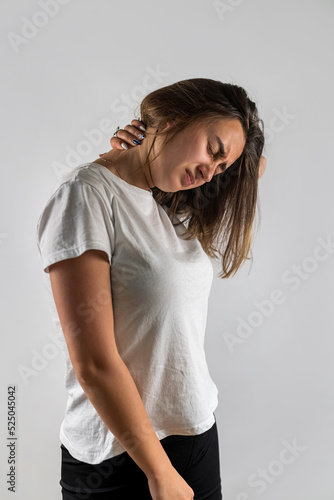 Young beautiful brunette with neck pain holding neck isolated on white background. © RomanR