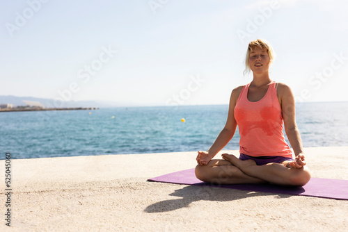 Beautiful young woman practising yoga outside. Fit woman doing stretching exercises at the beach.