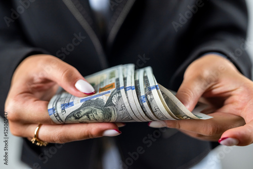 female hands in jacket showing pile of dollar banknotes and celebrating isolated on plain