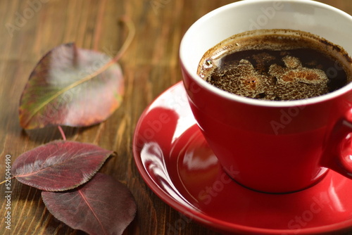 Сup of black coffee with red leaves. Fall composition.