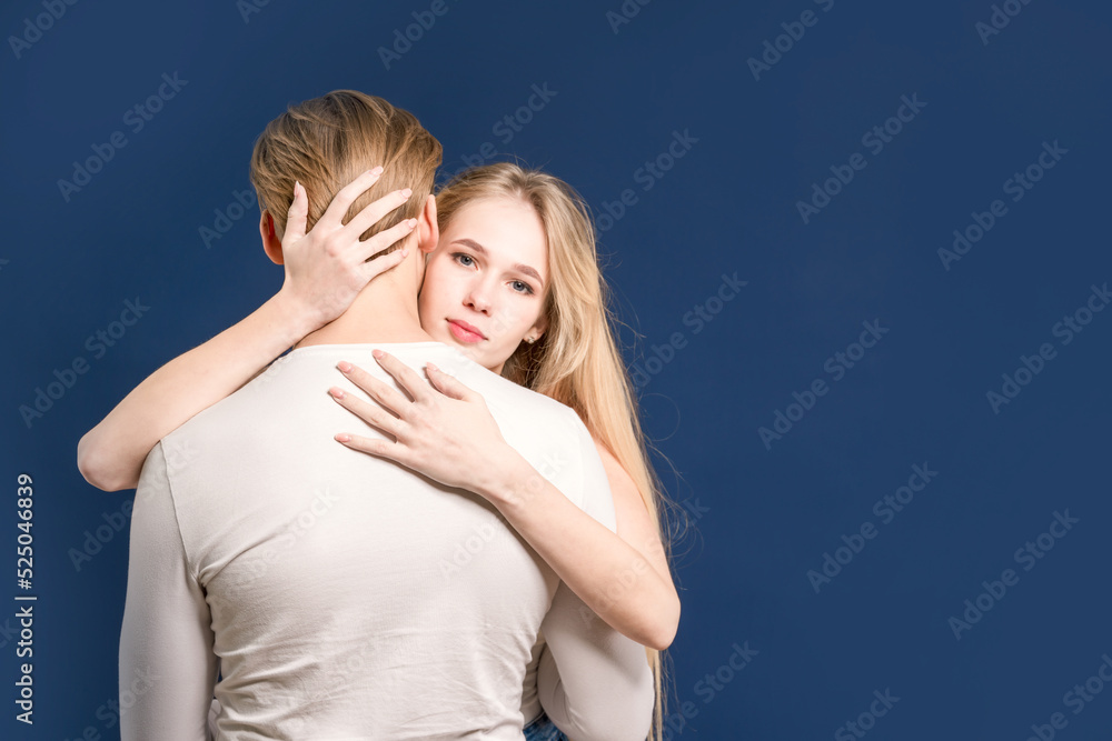 Beautiful girl hugging a guy on a dark blue background in the studio. Beautiful girl hugging a guy on a dark blue background in the studio.
