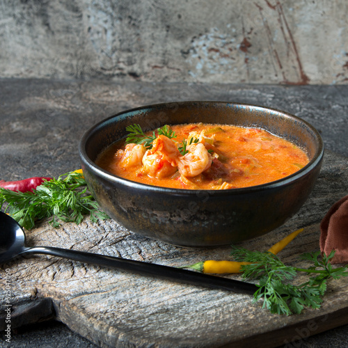 bowl of tomato soup with shrimp on a dark table