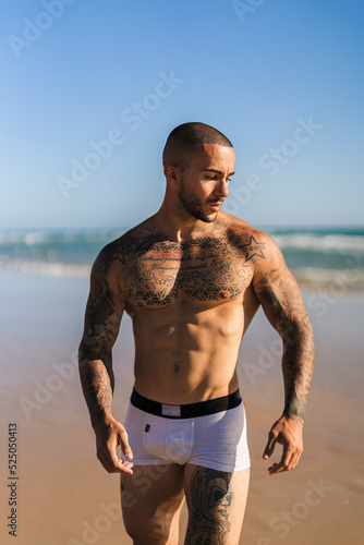 Chico joven tatuado y musculoso en bañador y ropa interior en la playa © MiguelAngelJunquera