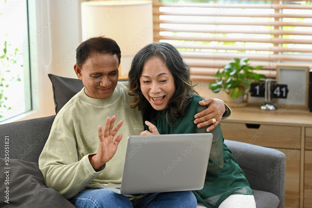 Happy retired couple having fun web surfing internet or making video call with family or friends on laptop together at home Happy retired couple having fun web surfing internet or making video call with family or friends on laptop together at home